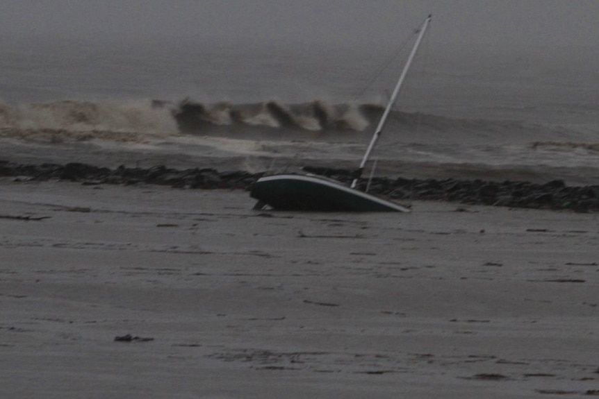 A small yacht aground on the Mersey breakwall