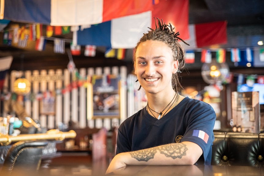 Nathan Barrierre sits behind a bar.