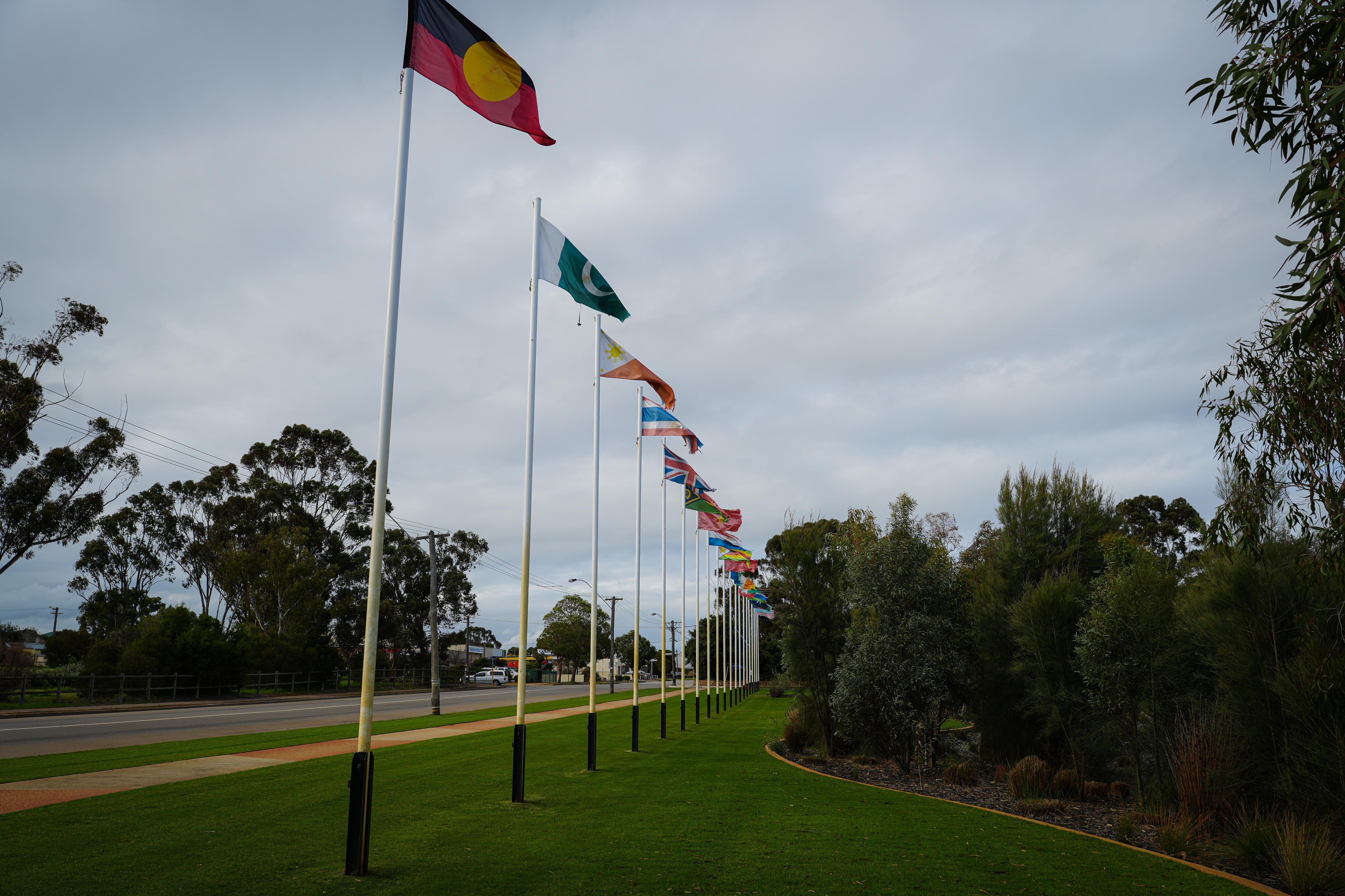 Una fila de banderas que representan múltiples nacionalidades izadas en un parque.