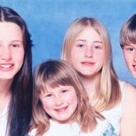 A portrait of three young girls and a boy against a blue backdrop