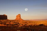 A full moon rises over Monument Valley Navajo Tribal Park