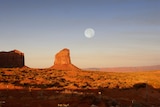 A full moon rises over Monument Valley Navajo Tribal Park