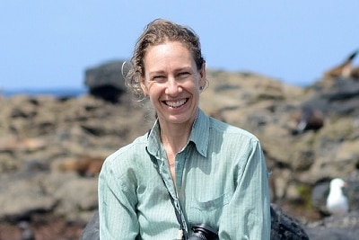 A woman sits on rocks smiling at the camera
