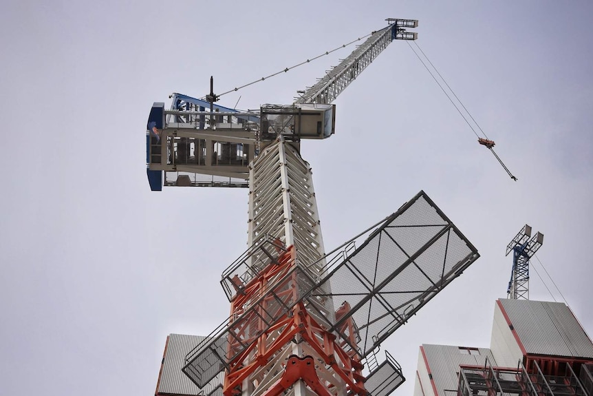 Looking up at a large construction crane looming overhead at a building site in Brisbane.