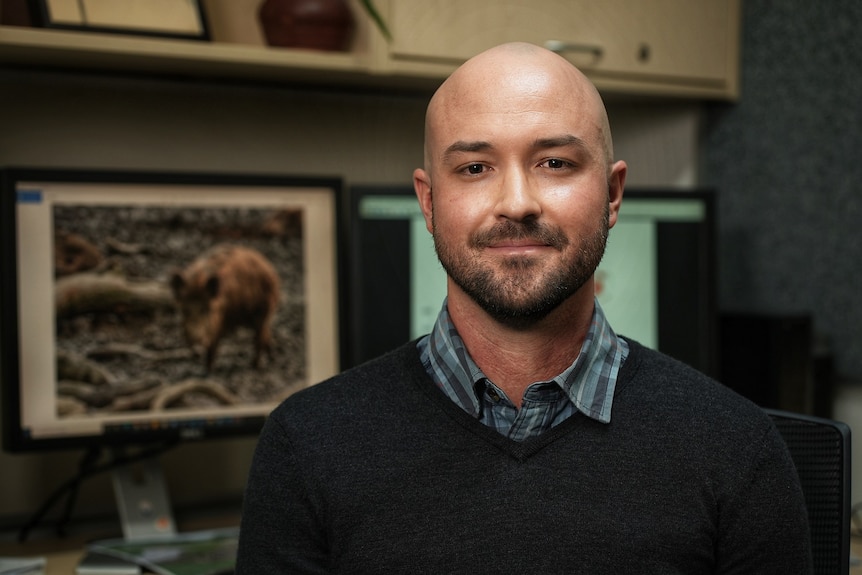 A man in an office smiles at the camera.