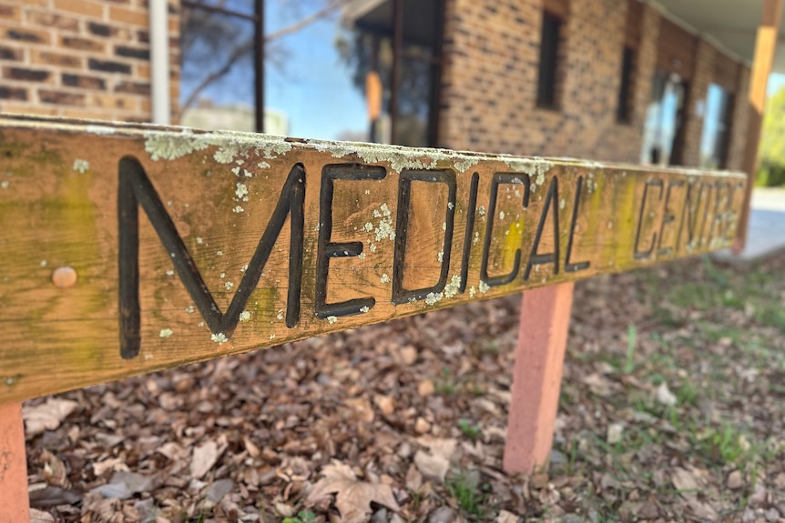 A low, wooden sign that reads "Medical Centre" outside a squat brick building.