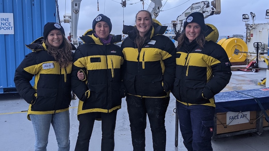 Four women scientists stand on the deck of a research ship in the Southern Ocean