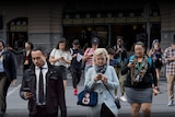 A photo illustration shows 11 people looking at their phones as they cross the road.