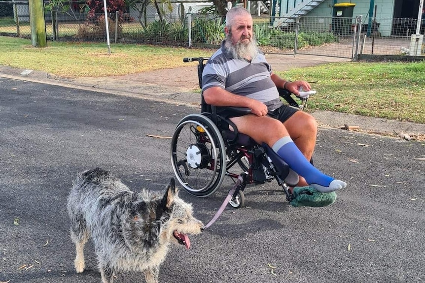 A man in a wheelchair pulling the dog