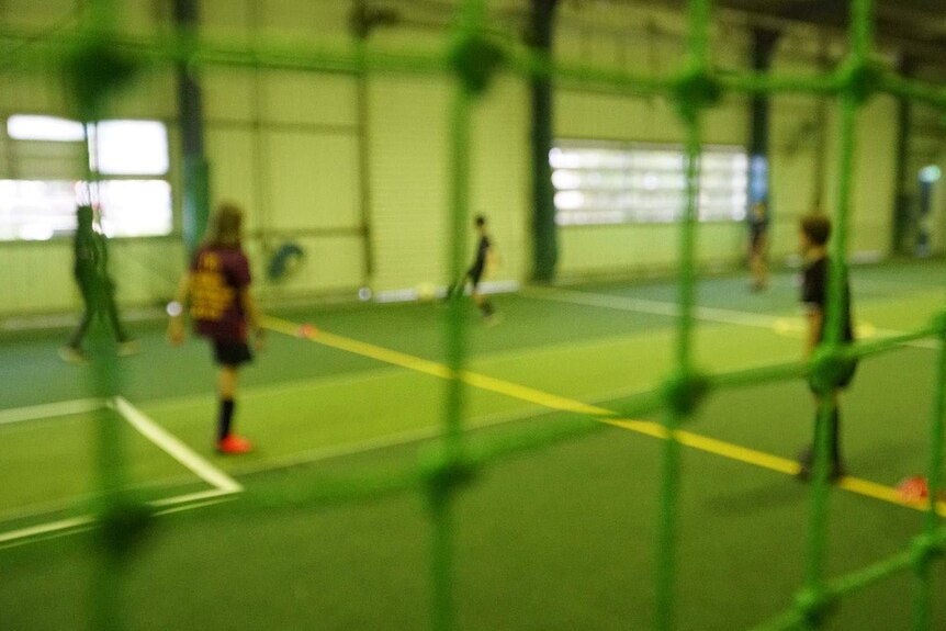 Blurred image of young people through a net inside a sports hall