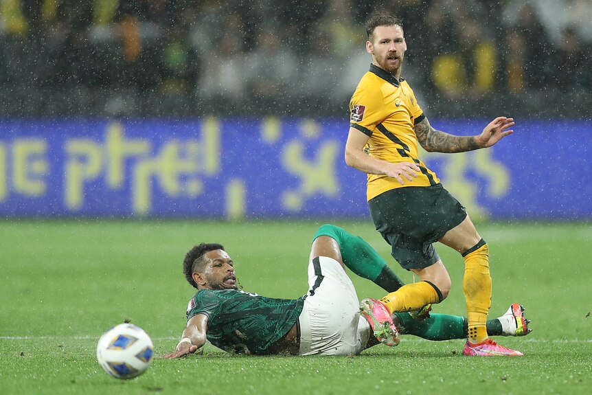 Martin Boyle looks towards the ball as a Saudi Arabia player slides at his feet