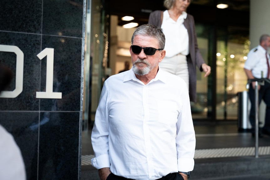 Daniel Martin Torrijos in a white shirt and dark glasses leaving a courthouse.