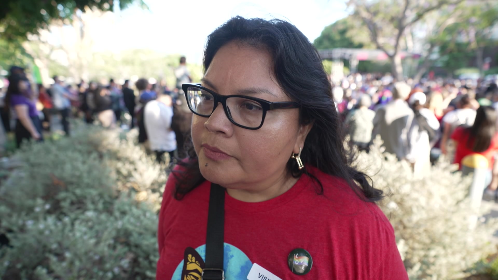 Mexican woman with tan skin and dark brown hair wearing a red shirt and glasses. 