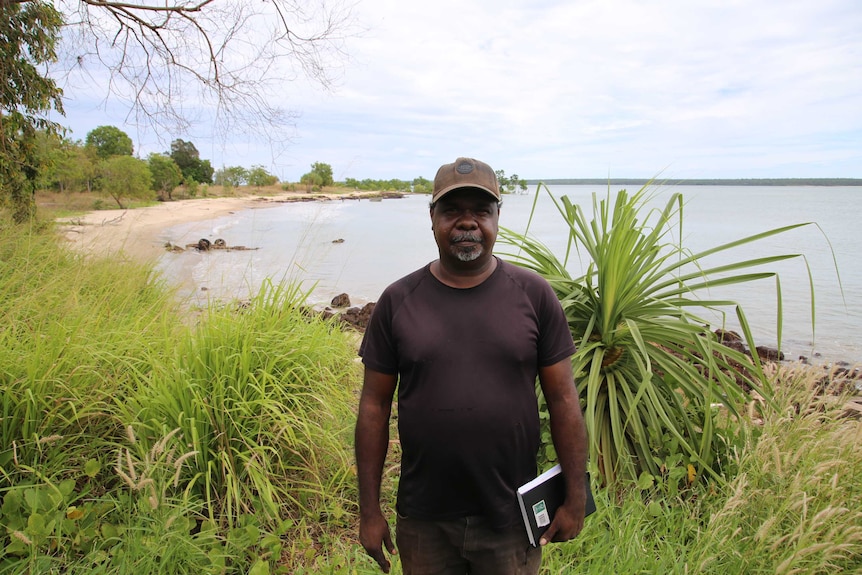 He stands outside by the water