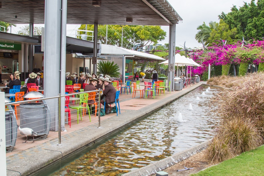 People eating at tables next to a pond at South Bank.