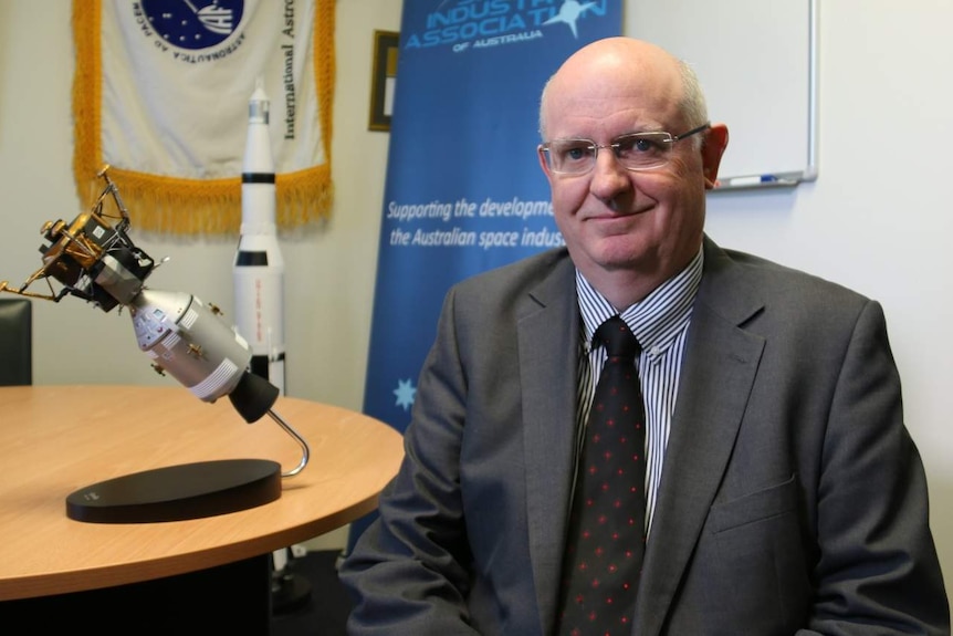 Michael Davis sits next to a space satellite model.