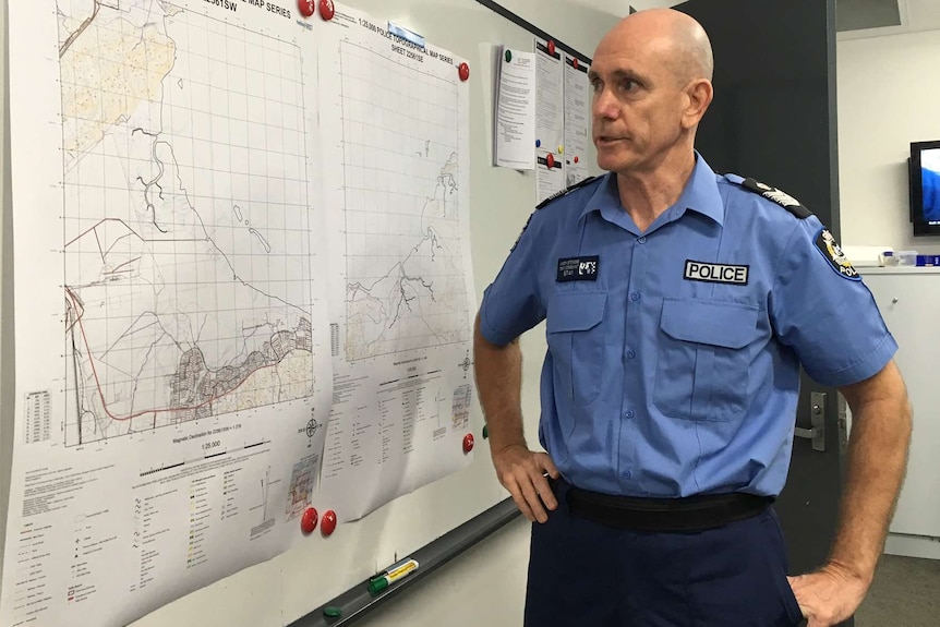 Karratha police Senior Sergeant Andy Stevens looks at a map of a search area on a whiteboard.