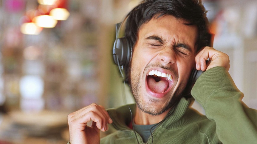 A man is singing his heart out with headphones on.