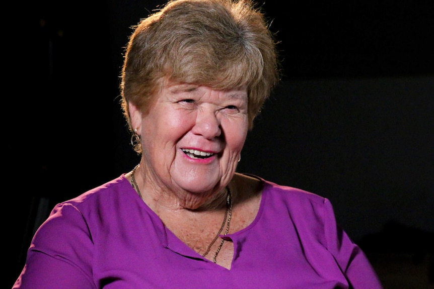 Woman smiles with black backdrop