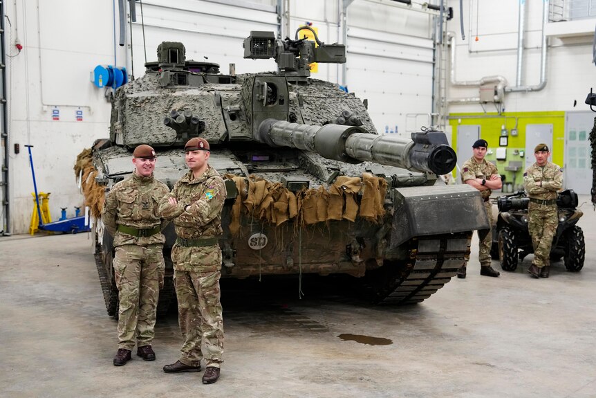 Two British military officers stand in front of a Challenger 2 tank.