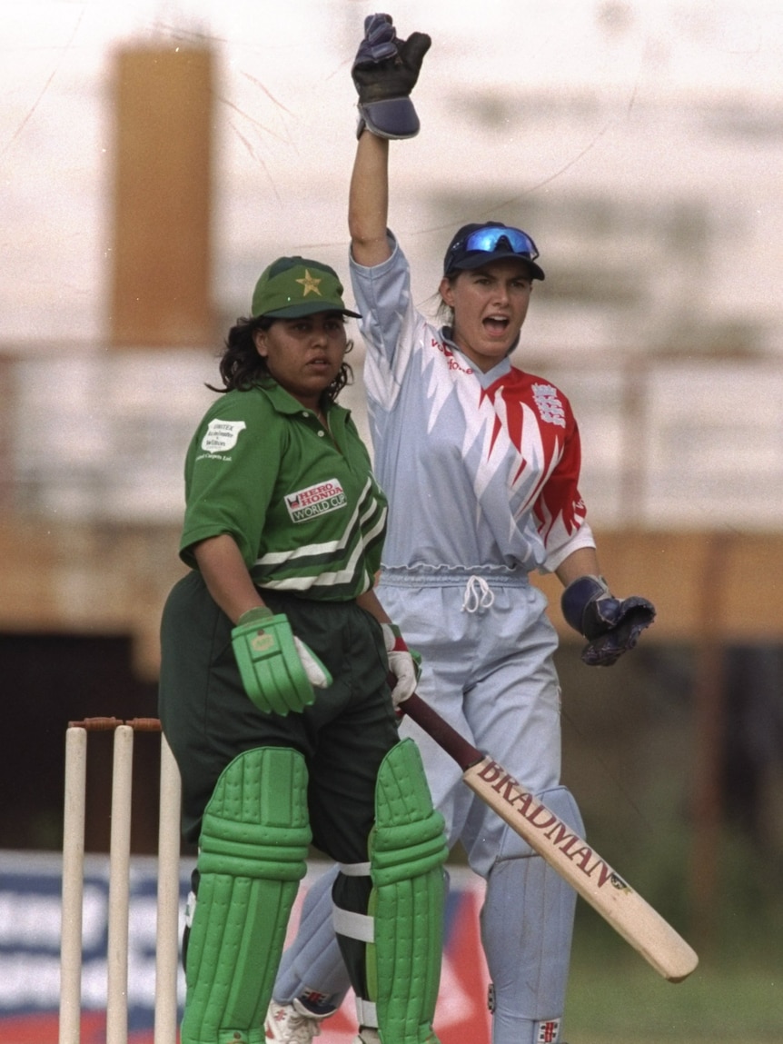 Shaiza Khan stands at the crease with her bat in her green and black Pakistan kit as the England wicketkeeper appeals behind