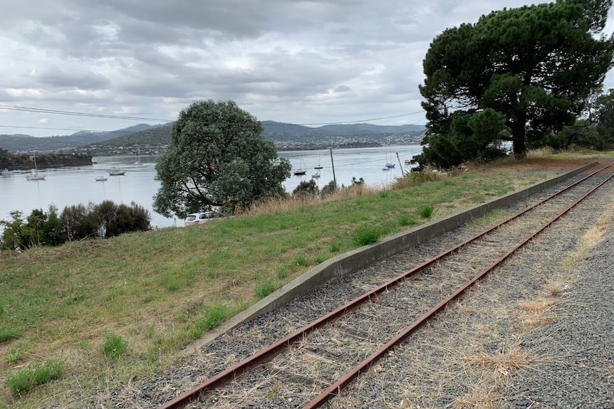 The original train platform at Cornelian Bay is seen here next to the water. Tracks run through the image.