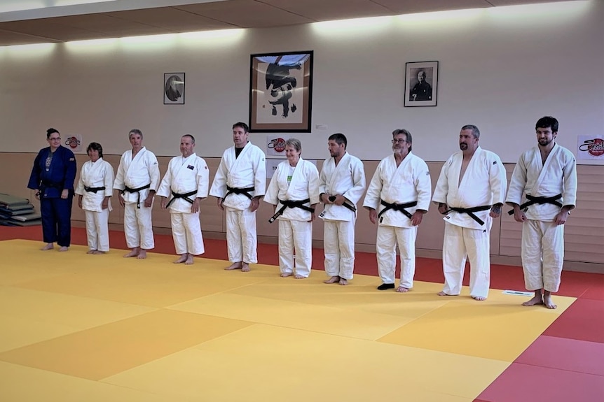 People stand in a line at a judo training session.