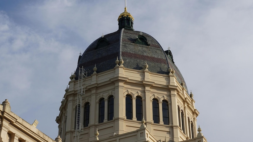 A mid shot of the building's dome with an Australian flag on top. 