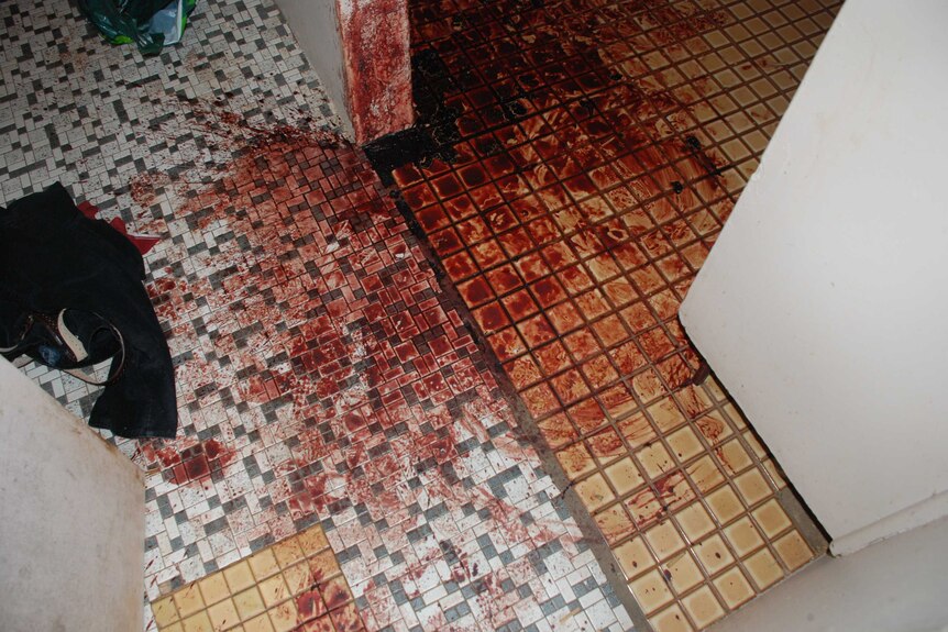 Dried blood covers a tiled floor in the flat belonging to Ray Niceforo. Discarded clothes are also visible.
