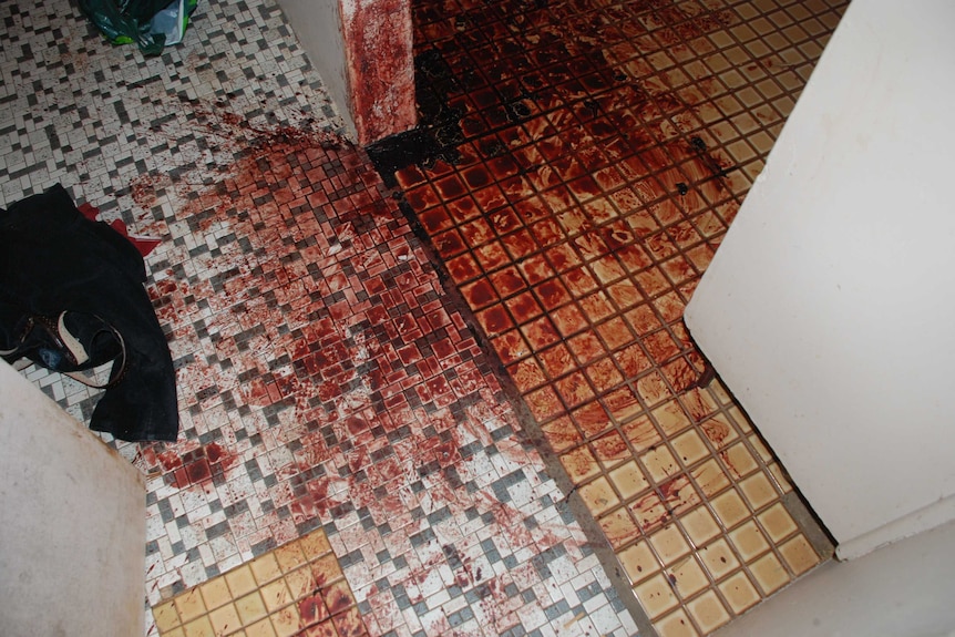 Dried blood covers a tiled floor in the flat belonging to Ray Niceforo. Discarded clothes are also visible.