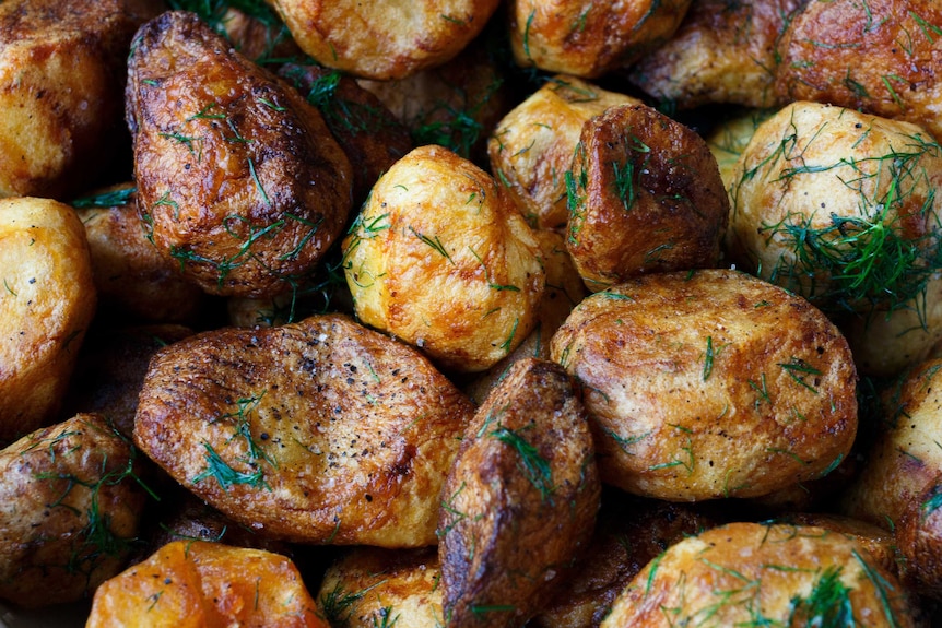 A close up of roasted potatoes with dill on them.