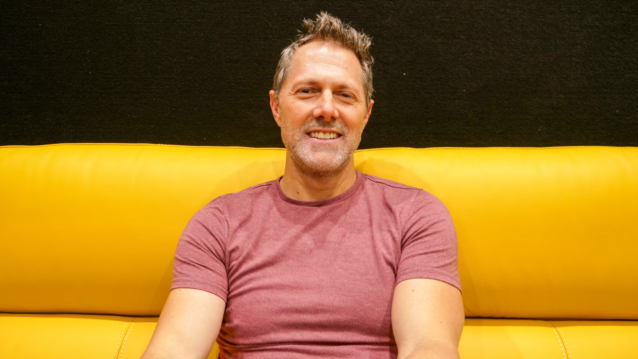 Un hombre se sienta en un sofá amarillo. 