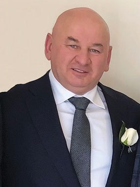 Un homme souriant et portant un costume et une cravate.