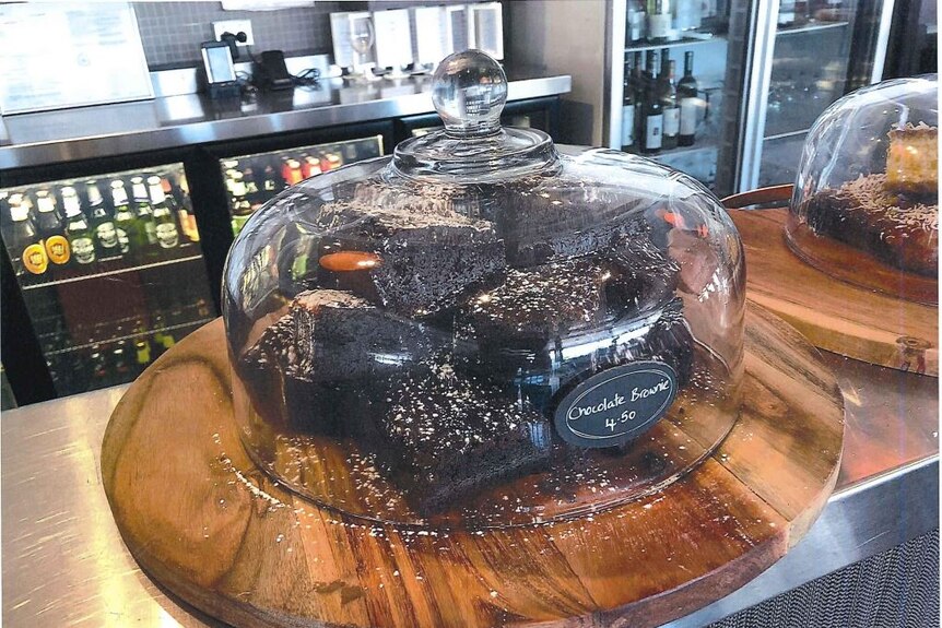 A glass bowl of brownies on the counter of a cafe.