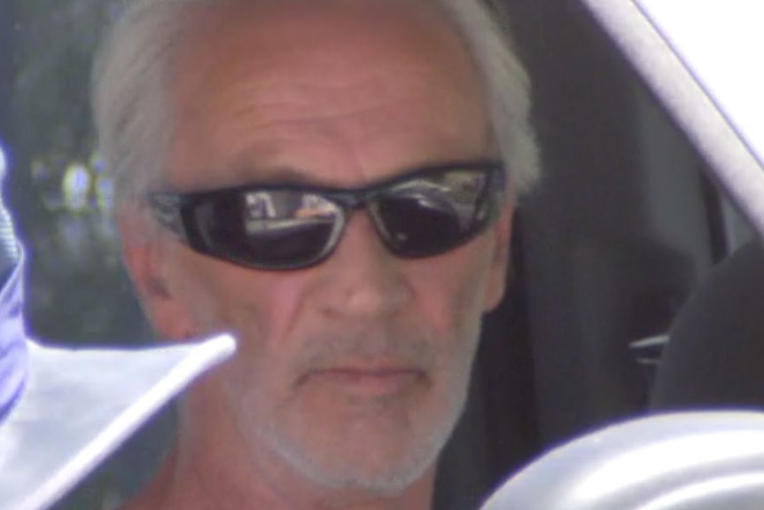 A close-up shot of Graham Leslie White in his vehicle wearing shades.