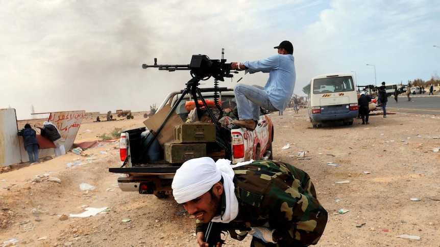 A Libyan rebel runs for cover as another fires a machine gun in the oil town of Ras Lanuf