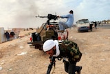 A Libyan rebel runs for cover as another fires a machine gun in the oil town of Ras Lanuf