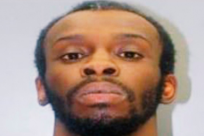 A man with short hair stares at the camera for a police mugshot