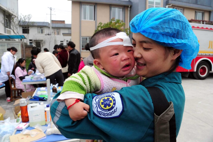 A Chinese medical worker holds an injured child.