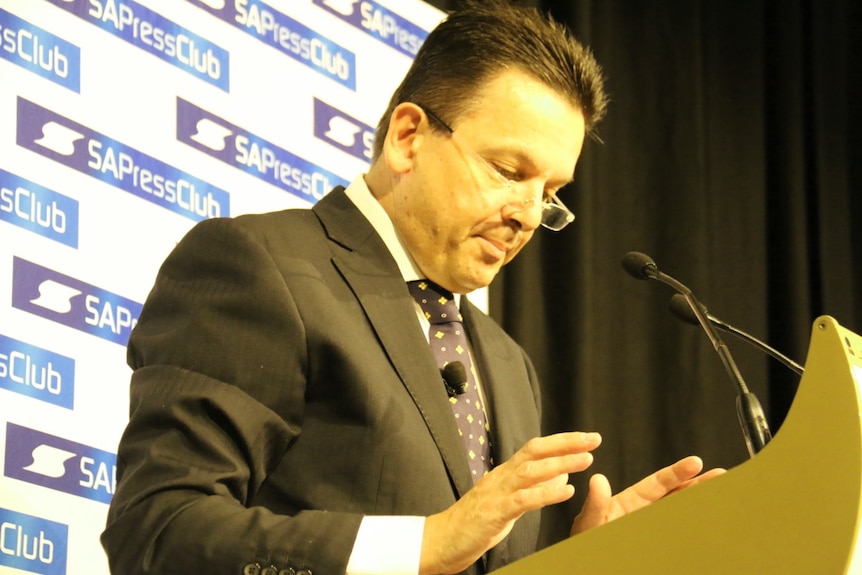 Nick Xenophon at a podium at the SA Press Club looking downward.