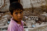 A Syrian boy walks past a burnt house in the Syrian village of Taremseh.