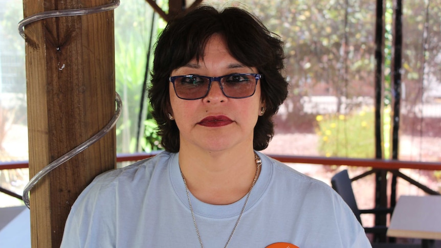 Headshot of a woman with short brown hair, wearing tinted glasses.