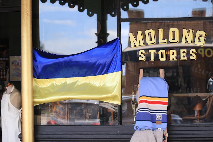 A Ukrainian flag hangs outside a store.