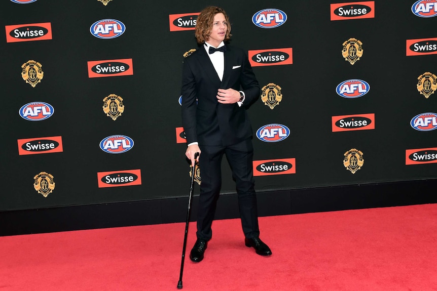 Nat Fyfe stands on the red carpet at the 2015 Brownlow Medal ceremony wearing a tuxedo and holding a cane.