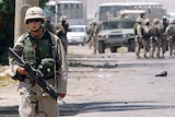 A US soldier patrols a Baghdad road where a Humvee vehicle was destroyed in an attack.