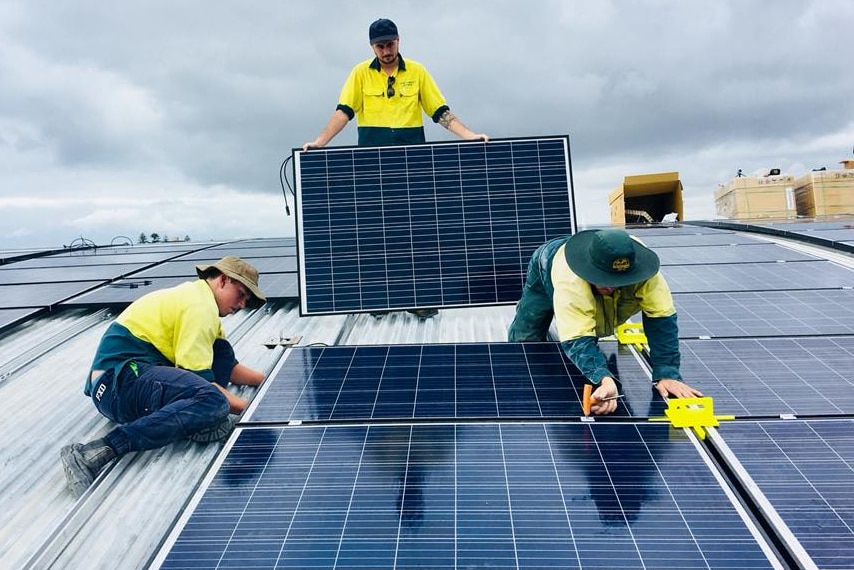 Instaladores de paneles solares en el techo de una escuela