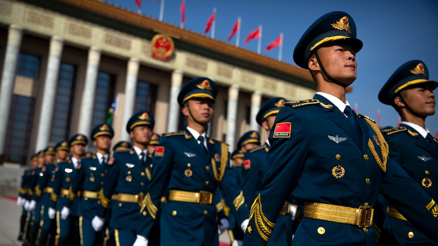 Members of a Chinese honour guard march in formation in full dress uniform.