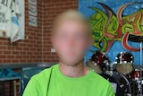 A young boy wearing a green shirt in a music room at a detention centre.