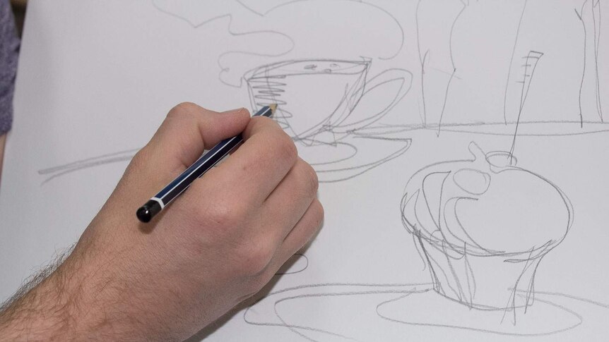 A man's hand drawing on white paper a picture of two teacups