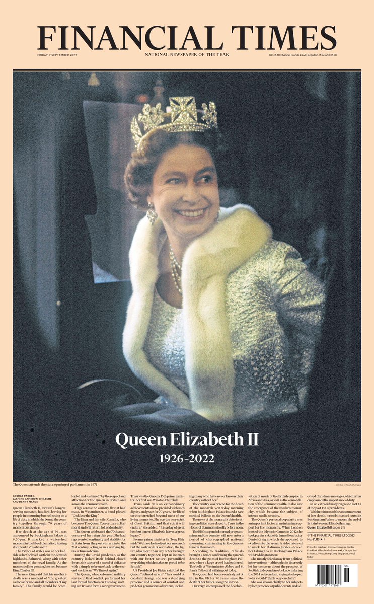 The Queen wears a silver jacket, a crown and smiles as she looks away from the camera.